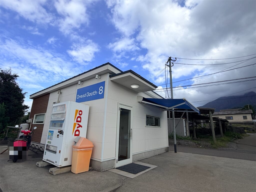 白い小さな建物に青い看板のパン屋さん「Bread Booth 8」の外観