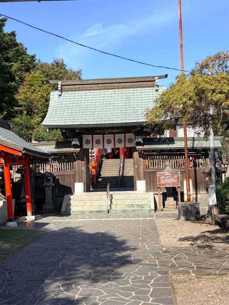 石畳の先に建つ霞神社の門と石段、朱色の柱