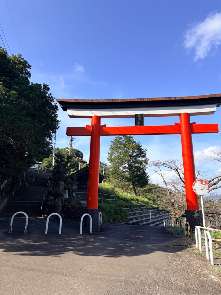 青空の下に立つ霞神社の朱色の鳥居と、奥へ続く参道