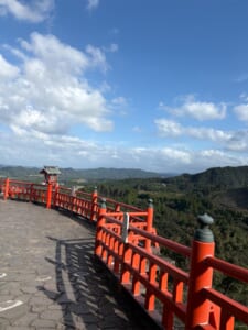 朱色の欄干が続く展望所と、その先に広がる山並みと青空