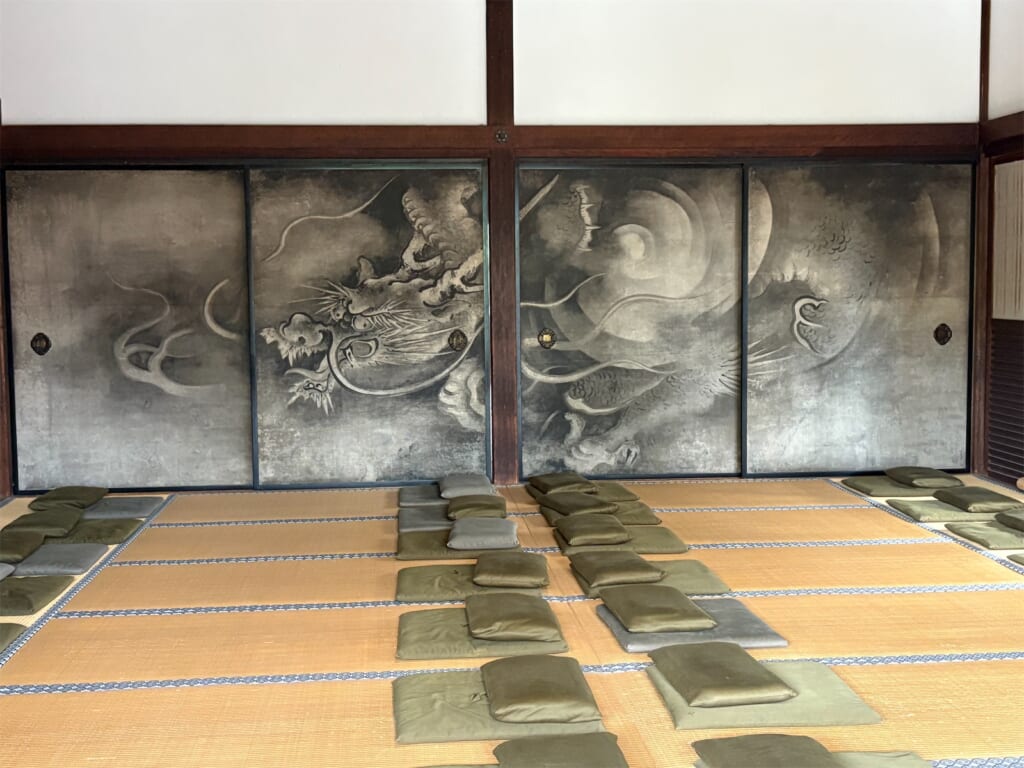 方丈の部屋の襖に描かれた墨の龍の絵と、畳に並ぶ座布団