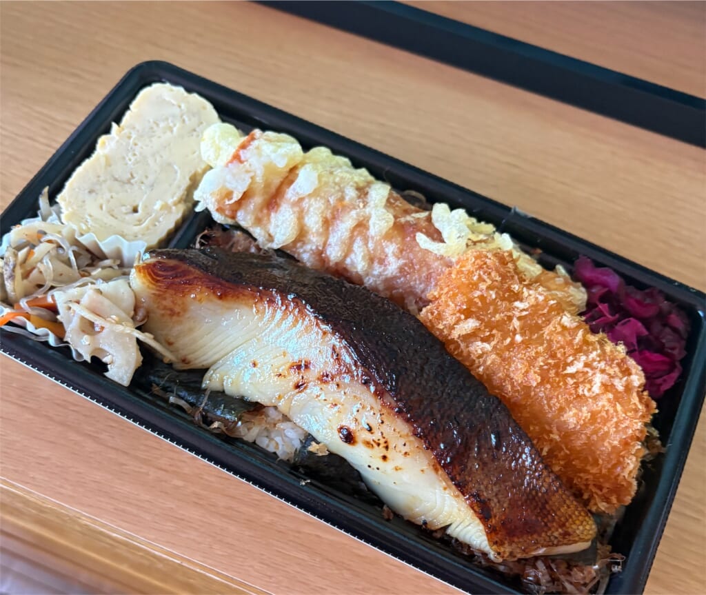 西京焼きの魚がのったお弁当。玉子焼きやフライが添えられている