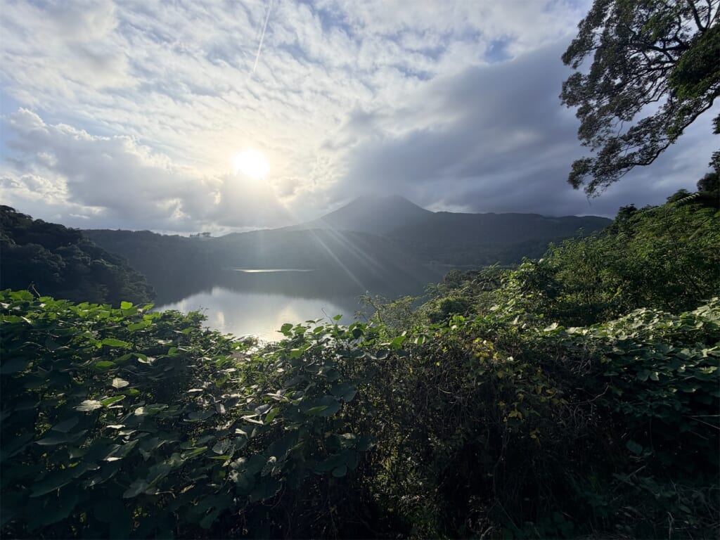 雲の切れ間から差す夕方の光と、山に囲まれた御池の湖面