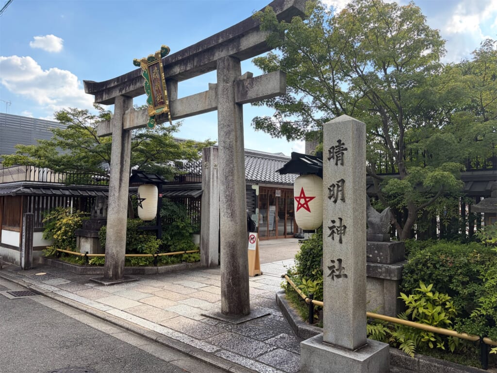 晴明神社の石の鳥居と「晴明神社」と刻まれた社号標、星のマークの提灯